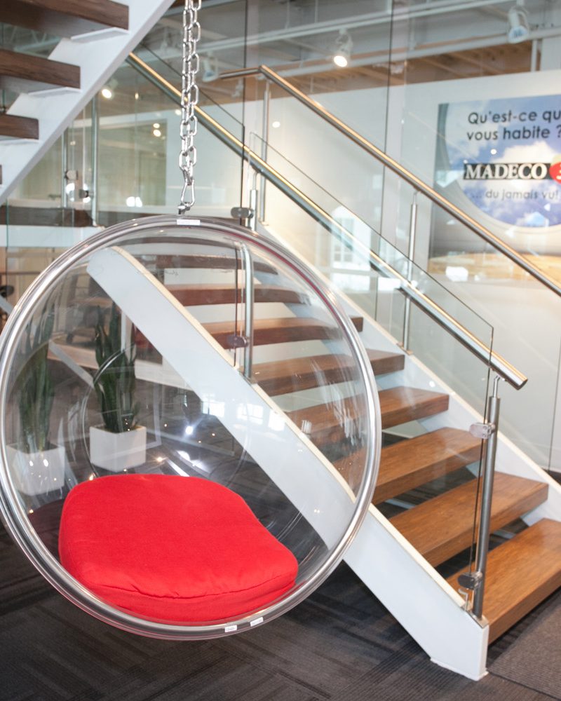 L'escalier vitré des bureaux de Madeco et un fauteuil suspendu rouge